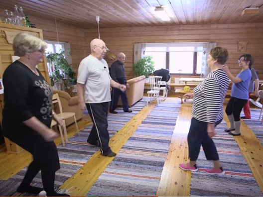 Ikäihmiset jumppaavat ryhmänä kodin olohuoneessa