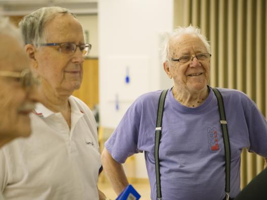 Kolme iäkästä miestä kuuntelemassa ohjeita likuntaryhmässä. 