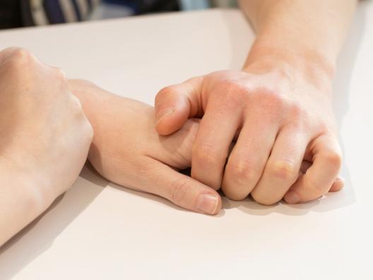 Kaksi ihmistä pitävät toisiaan kädestä kiinni.