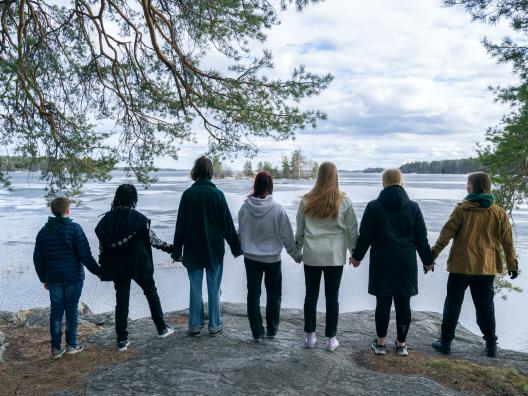 Nuoret seisovat rannalla käsi kädessä