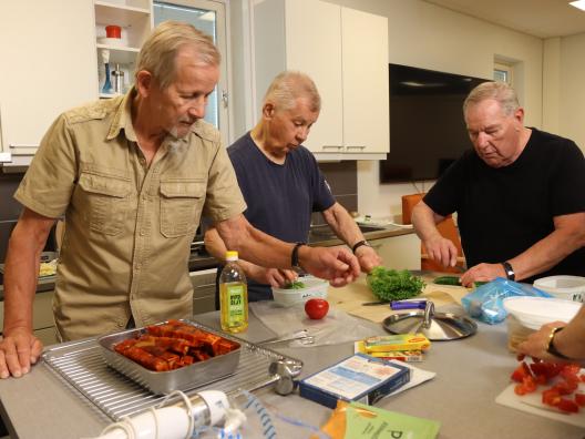Eläkeikäiset miehet laittamassa ruokaa yhdessä