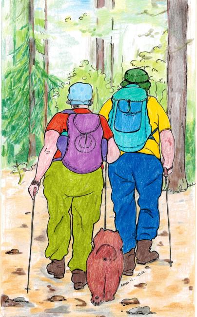 Mies, nainen ja koira kävelyllä metsässä.