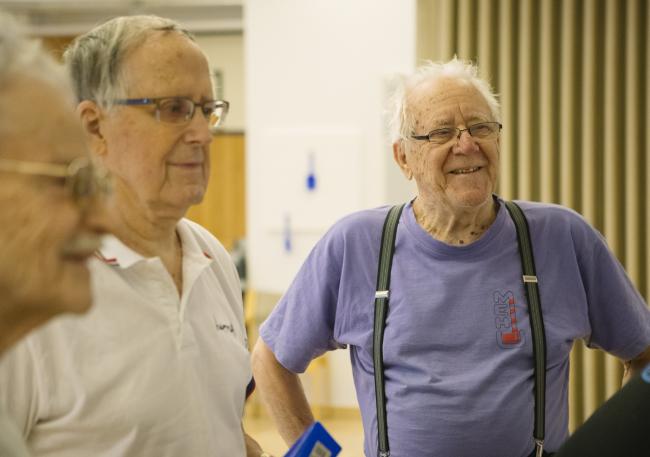 Kolme iäkästä miestä kuuntelemassa ohjeita likuntaryhmässä. 