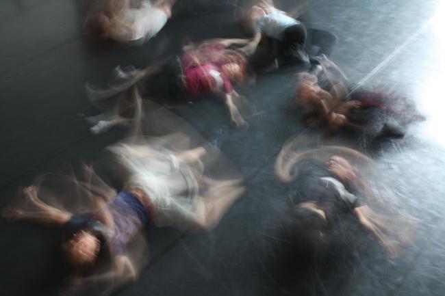 Kuva teoksesta Kadonneet pojat (2010). Kuvassa on kuusi nuorta miestä, jotka liikkuvat vimmaisesti lattialla maaten. 