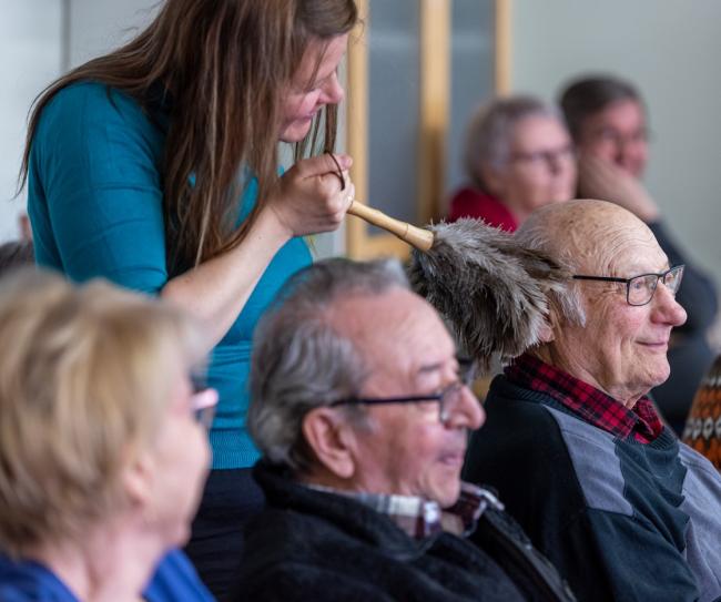 Kuvassa nainen kutittelee seniorin hiuksia huiskulla. 