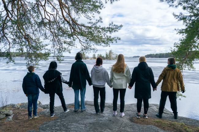 Nuoret seisovat rannalla käsi kädessä